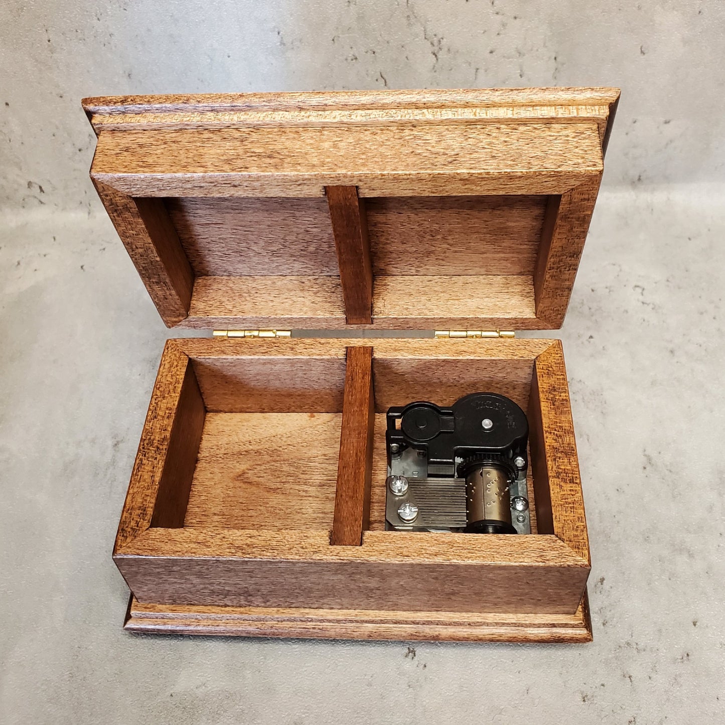 jewelry box with an open lid showing compartments, one with music box movement inside