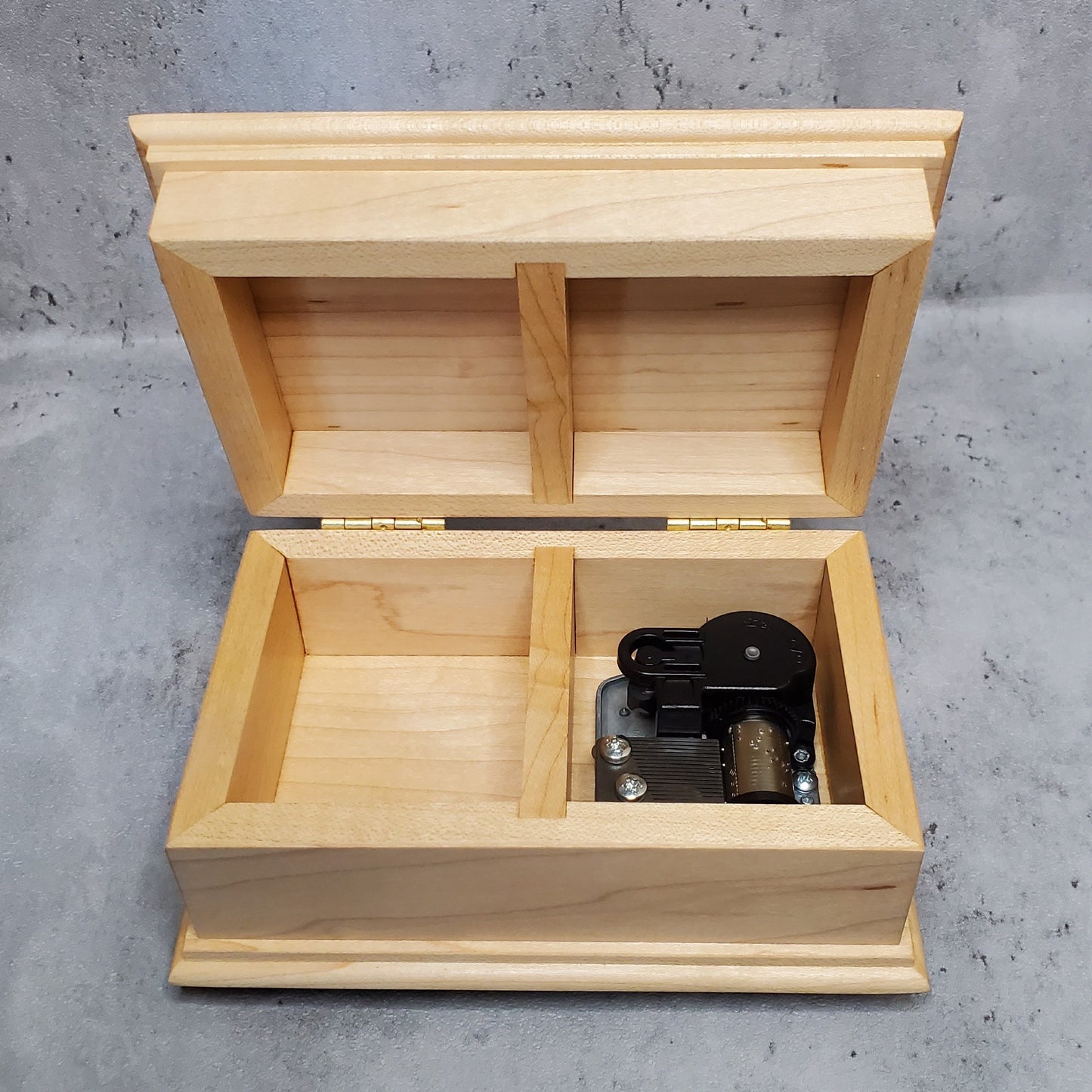 Open lid jewelry box showing wind up music box movement inside