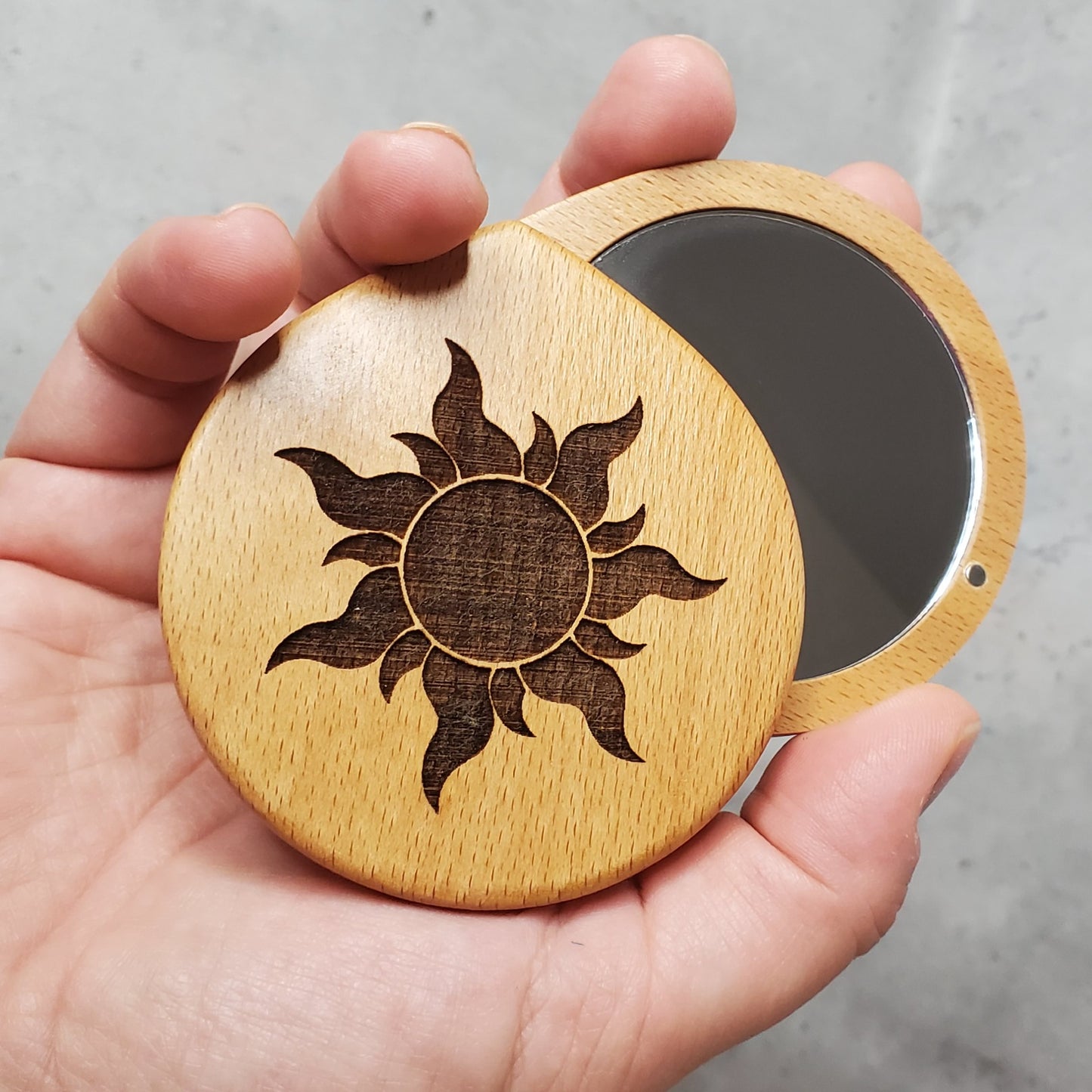 Pocket mirror with sun engraved on the top, round shape, twist to open